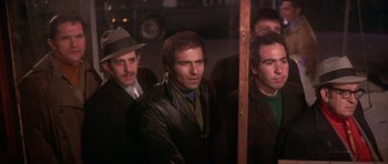 Movie still from “The Owl and the Pussycat” (1970), directed by Herbert Ross – A group of men standing next to each other in a room; Medium shot, Low angle