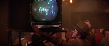 Movie still from “The Owl and the Pussycat” (1970), directed by Herbert Ross – A man in a hat is watching a television screen; Medium shot, Over the shoulder angle