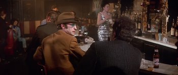 Movie still from “The Owl and the Pussycat” (1970), directed by Herbert Ross – A group of people sitting at a table with drinks; Medium shot, Over the shoulder angle