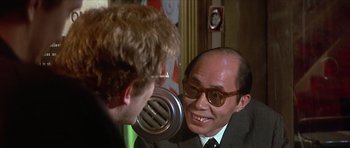 Movie still from “The Owl and the Pussycat” (1970), directed by Herbert Ross – A man wearing a suit and tie talking to another man wearing glasses; Close Up shot, Over the shoulder angle