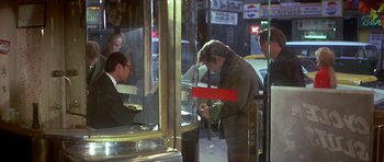 Movie still from “The Owl and the Pussycat” (1970), directed by Herbert Ross – A man standing in front of a store window looking at his phone; Medium shot, Over the shoulder angle