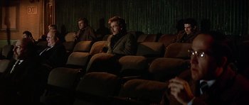 Movie still from “The Owl and the Pussycat” (1970), directed by Herbert Ross – Two men sitting in a theater with one of them looking at the camera; Wide shot, High angle