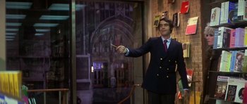 Movie still from “The Owl and the Pussycat” (1970), directed by Herbert Ross – A man in a suit and tie holding a wand in his hand; Medium shot, Low angle
