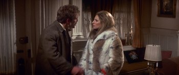 Movie still from “The Owl and the Pussycat” (1970), directed by Herbert Ross – A man and a woman in a fur coat shaking hands in a room; Medium shot, Over the shoulder angle