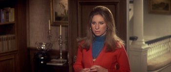 Movie still from “The Owl and the Pussycat” (1970), directed by Herbert Ross – A woman in a red sweater standing next to a candle holder; Medium shot, Over the shoulder angle