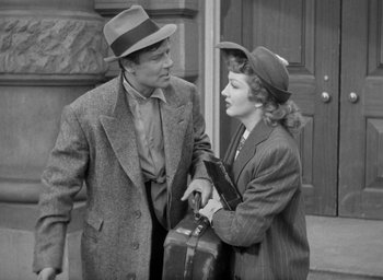 Movie still from “The Palm Beach Story” (1942), directed by Preston Sturges – A man and a woman standing next to each other holding suitcases; Medium shot, High angle