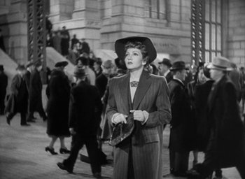 Movie still from “The Palm Beach Story” (1942), directed by Preston Sturges – An old photo of a woman in a suit and a hat; Wide shot, High angle