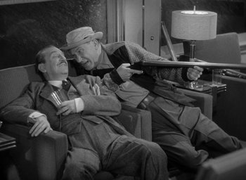 Movie still from “The Palm Beach Story” (1942), directed by Preston Sturges – A couple of men sitting next to each other on a couch; Medium shot, High angle