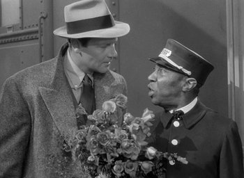 Movie still from “The Palm Beach Story” (1942), directed by Preston Sturges – A man in a hat and a man in a suit holding a bouquet of flowers; Medium shot, Over the shoulder angle