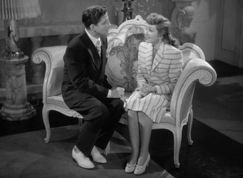 Movie still from “The Palm Beach Story” (1942), directed by Preston Sturges – A man and a woman sitting on a couch; Wide shot, High angle