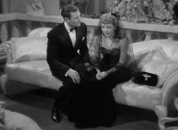 Movie still from “The Palm Beach Story” (1942), directed by Preston Sturges – A man and a woman sitting on a couch in formal wear; Medium shot, High angle