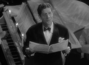 Movie still from “The Palm Beach Story” (1942), directed by Preston Sturges – A man in a suit and bow tie holding a sheet of paper; Close Up shot, High angle