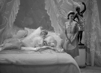Movie still from “The Palm Beach Story” (1942), directed by Preston Sturges – An old photo of a woman standing next to a little girl; Wide shot, High angle
