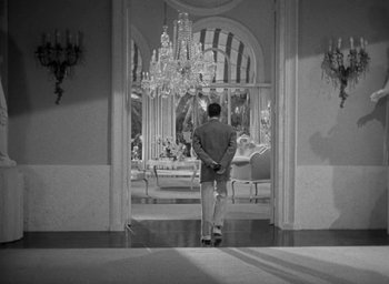 Movie still from “The Palm Beach Story” (1942), directed by Preston Sturges – A black and white photo of a man standing in front of a mirror; Extreme Wide shot, High angle