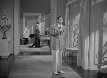 Movie still from “The Palm Beach Story” (1942), directed by Preston Sturges – A black and white photo of a man in a suit; Wide shot, Low angle