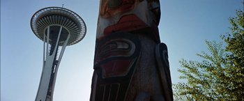 Movie still from “The Parallax View” (1974), directed by Alan J. Pakula – A totem pole with a space needle in the background; Extreme Wide shot, Low angle