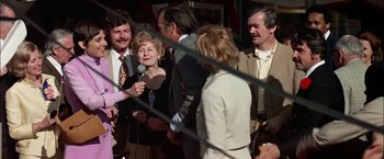 Movie still from “The Parallax View” (1974), directed by Alan J. Pakula – A group of people standing next to each other; Medium shot, Over the shoulder angle