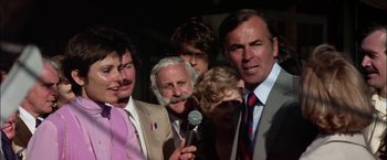 Movie still from “The Parallax View” (1974), directed by Alan J. Pakula – A group of men and women standing next to each other; Close Up shot, Over the shoulder angle