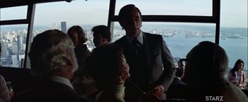 Movie still from “The Parallax View” (1974), directed by Alan J. Pakula – A group of people sitting at a table in front of a large window; Medium shot, Over the shoulder angle