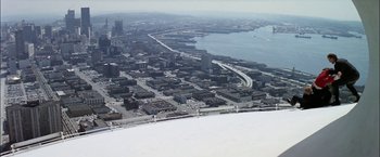 Movie still from “The Parallax View” (1974), directed by Alan J. Pakula – An aerial view of a city with a bridge in the background; Extreme Wide shot, High angle