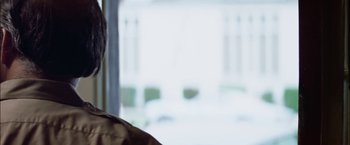 Movie still from “The Parallax View” (1974), directed by Alan J. Pakula – A person sitting in front of a large window; Close Up shot, Over the shoulder angle