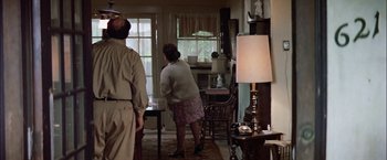 Movie still from “The Parallax View” (1974), directed by Alan J. Pakula – A woman standing in a living room next to a man; Wide shot, High angle