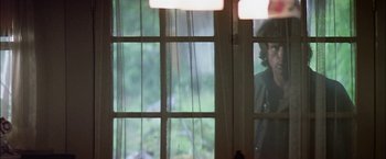 Movie still from “The Parallax View” (1974), directed by Alan J. Pakula – A woman standing in front of a window looking outside; Medium shot, Low angle