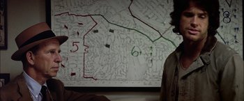 Movie still from “The Parallax View” (1974), directed by Alan J. Pakula – A man standing in front of a large map; Close Up shot, Overhead angle
