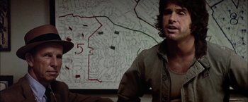 Movie still from “The Parallax View” (1974), directed by Alan J. Pakula – A man standing in front of a map of a city; Close Up shot, Over the shoulder angle