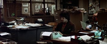 Movie still from “The Parallax View” (1974), directed by Alan J. Pakula – A man sitting at a desk typing on a typewriter; Medium shot, High angle
