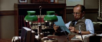 Movie still from “The Parallax View” (1974), directed by Alan J. Pakula – A man sitting at a table reading a paper; Medium shot, Over the shoulder angle