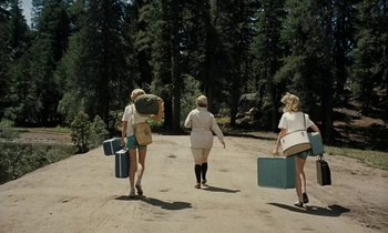 Movie still from “The Parent Trap” (1961), directed by David Swift – A group of women walking down a dirt road carrying suitcases; Wide shot, Low angle