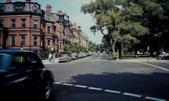 Movie still from “The Parent Trap” (1961), directed by David Swift – A car driving down a street next to a row of buildings; Extreme Wide shot, High angle
