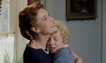 Movie still from “The Parent Trap” (1961), directed by David Swift – A woman and a child hugging each other in front of a painting; Medium shot, Low angle