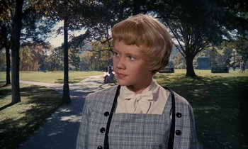 Movie still from “The Parent Trap” (1961), directed by David Swift – A young girl standing in a park near a tree; Close Up shot, Over the shoulder angle