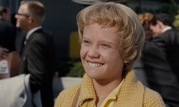 Movie still from “The Parent Trap” (1961), directed by David Swift – A young woman smiling for the camera while wearing a yellow sweater; Close Up shot, Low angle