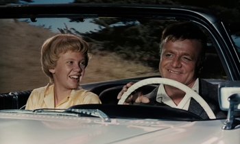 Movie still from “The Parent Trap” (1961), directed by David Swift – A man and a woman driving a car in the road; Medium shot, Low angle