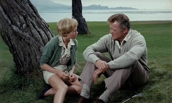 Movie still from “The Parent Trap” (1961), directed by David Swift – A man and a woman sitting in the grass; Medium shot, Over the shoulder angle
