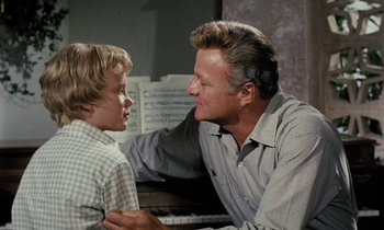 Movie still from “The Parent Trap” (1961), directed by David Swift – A man and a young boy sitting next to each other; Medium shot, Over the shoulder angle