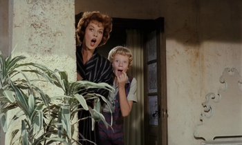 Movie still from “The Parent Trap” (1961), directed by David Swift – A woman standing next to a child in a doorway; Medium shot, Low angle