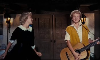 Movie still from “The Parent Trap” (1961), directed by David Swift – A young boy holding a guitar while a young girl looks on; Medium shot, Low angle
