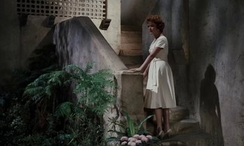 Movie still from “The Parent Trap” (1961), directed by David Swift – A woman standing next to a stone wall; Wide shot, High angle