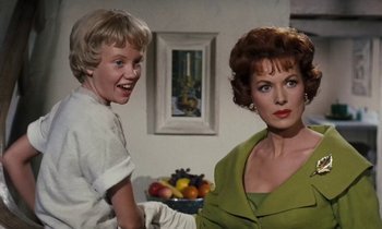 Movie still from “The Parent Trap” (1961), directed by David Swift – A woman and a boy are sitting in a living room; Medium shot, Over the shoulder angle