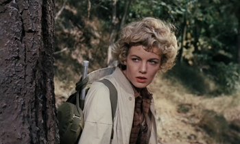 Movie still from “The Parent Trap” (1961), directed by David Swift – A woman with a backpack standing next to a tree in the woods; Close Up shot, Low angle