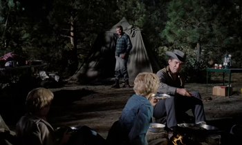 Movie still from “The Parent Trap” (1961), directed by David Swift – A group of people sitting in front of a teepee; Wide shot, Over the shoulder angle