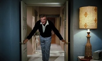 Movie still from “The Parent Trap” (1961), directed by David Swift – A man standing in a hallway holding on to a door handle; Medium shot, Low angle