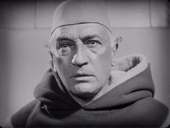 An older man wearing a monk's robe and hat