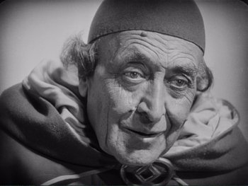 An old man wearing a hat and a cape