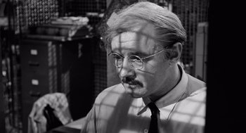 Movie still from “The Pawnbroker” (1964), directed by Sidney Lumet – A man with a mustache wearing glasses and a tie; Close Up shot, Over the shoulder angle