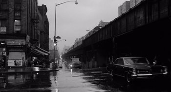 Movie still from “The Pawnbroker” (1964), directed by Sidney Lumet – A black - and - white photo of a city street with cars parked on the side; Extreme Wide shot, Low angle